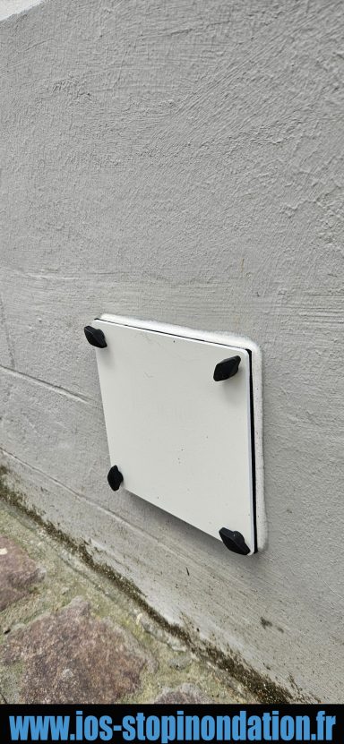 Plaque étanche Plaque blanche fixée au mur, avec des coins noirs, sur un fond gris.